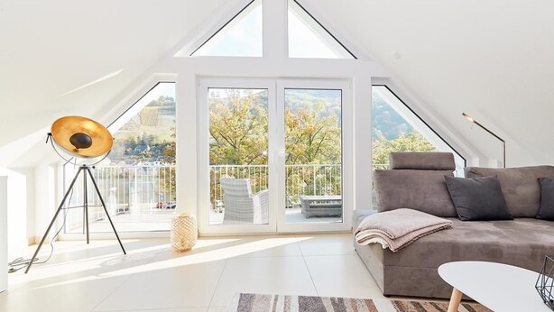 A spacious room with a sloped ceiling, a large window, a sofa, a coffee table, and a tripod lamp. - Bella Vista (Bernkastel-Kues)
