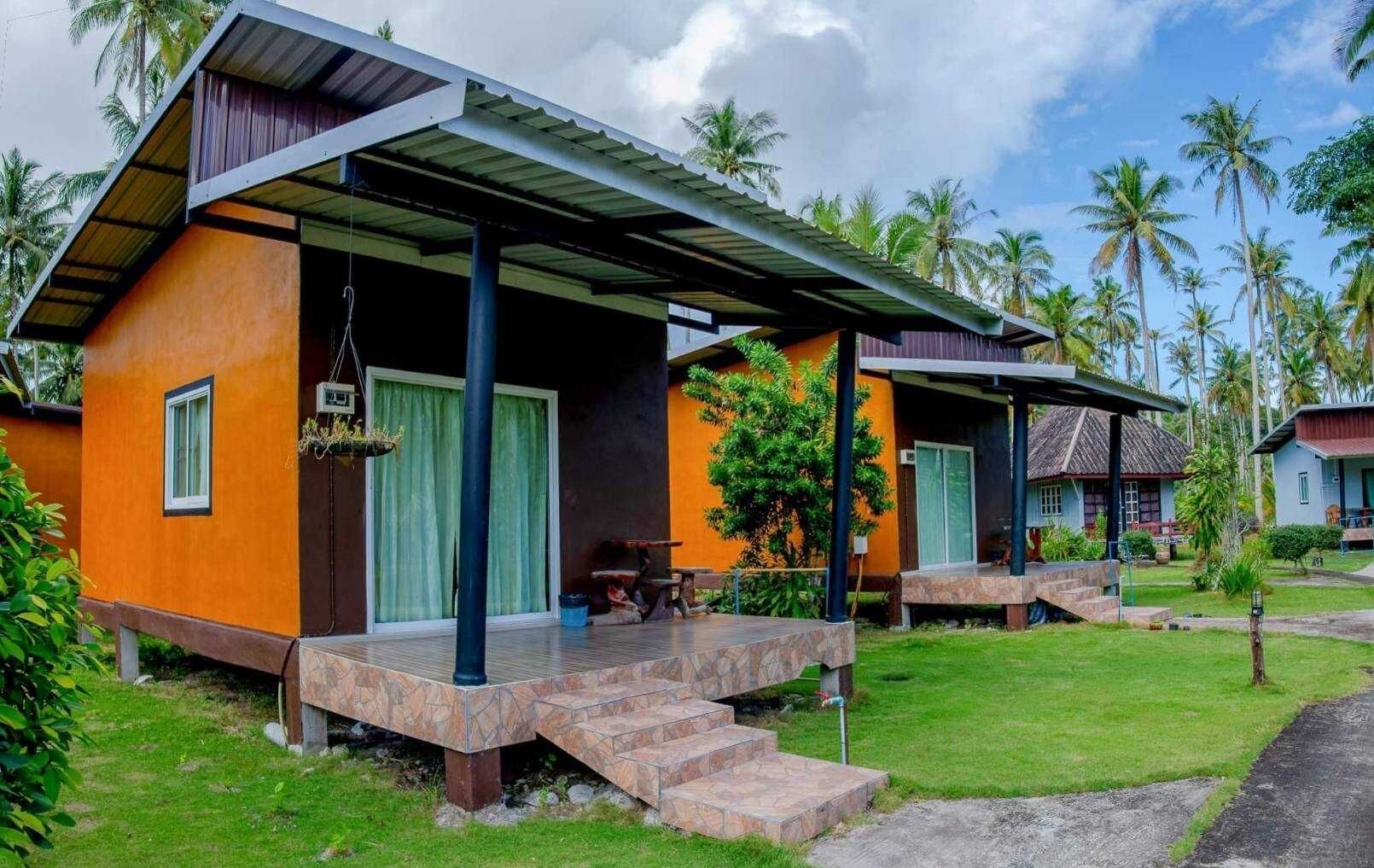 A bungalow with a covered porch, a small outdoor seating area, and a staircase leading to the entrance.