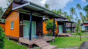 A bungalow with a covered porch, a small outdoor seating area, and a staircase leading to the entrance.