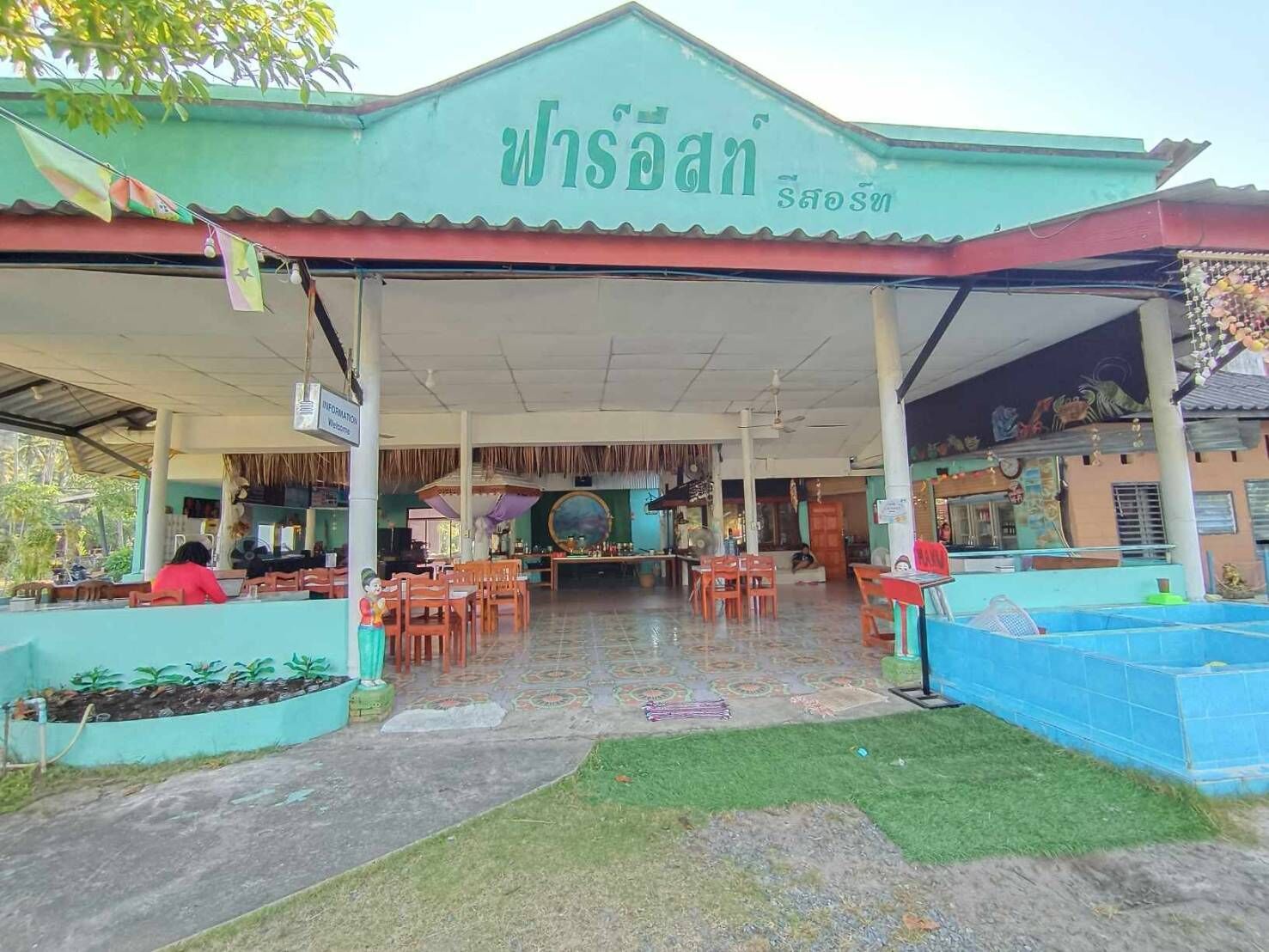 Un restaurante con zona de estar al aire libre cubierta, un letrero y piso de baldosas.