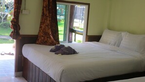 A hotel room with a bed, a window with curtains, and a view of the outdoors.