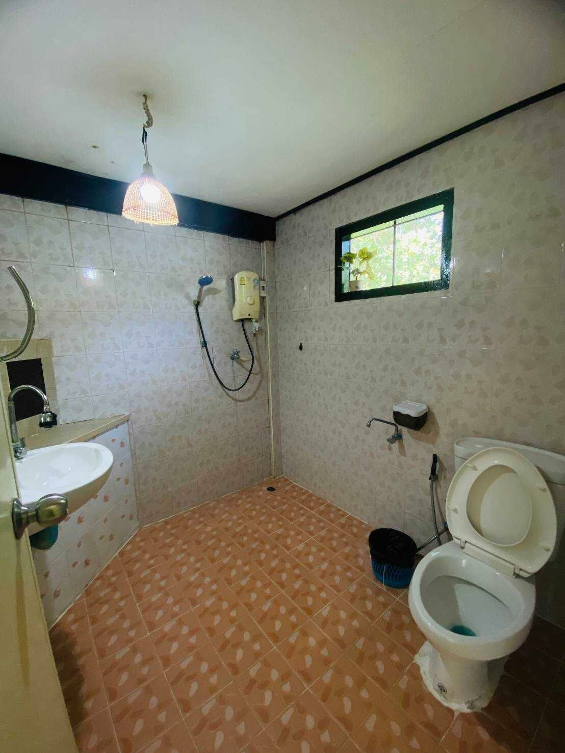 Un baño con lavamanos, inodoro, ducha y una ventana pequeña.