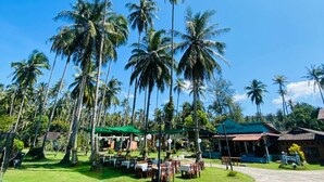 A tropical resort with palm trees, outdoor seating, and a clear blue sky.