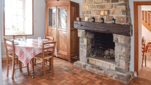 Un coin repas agrémenté d’une cheminée en pierre, d’une table à manger en bois et de chaises.
