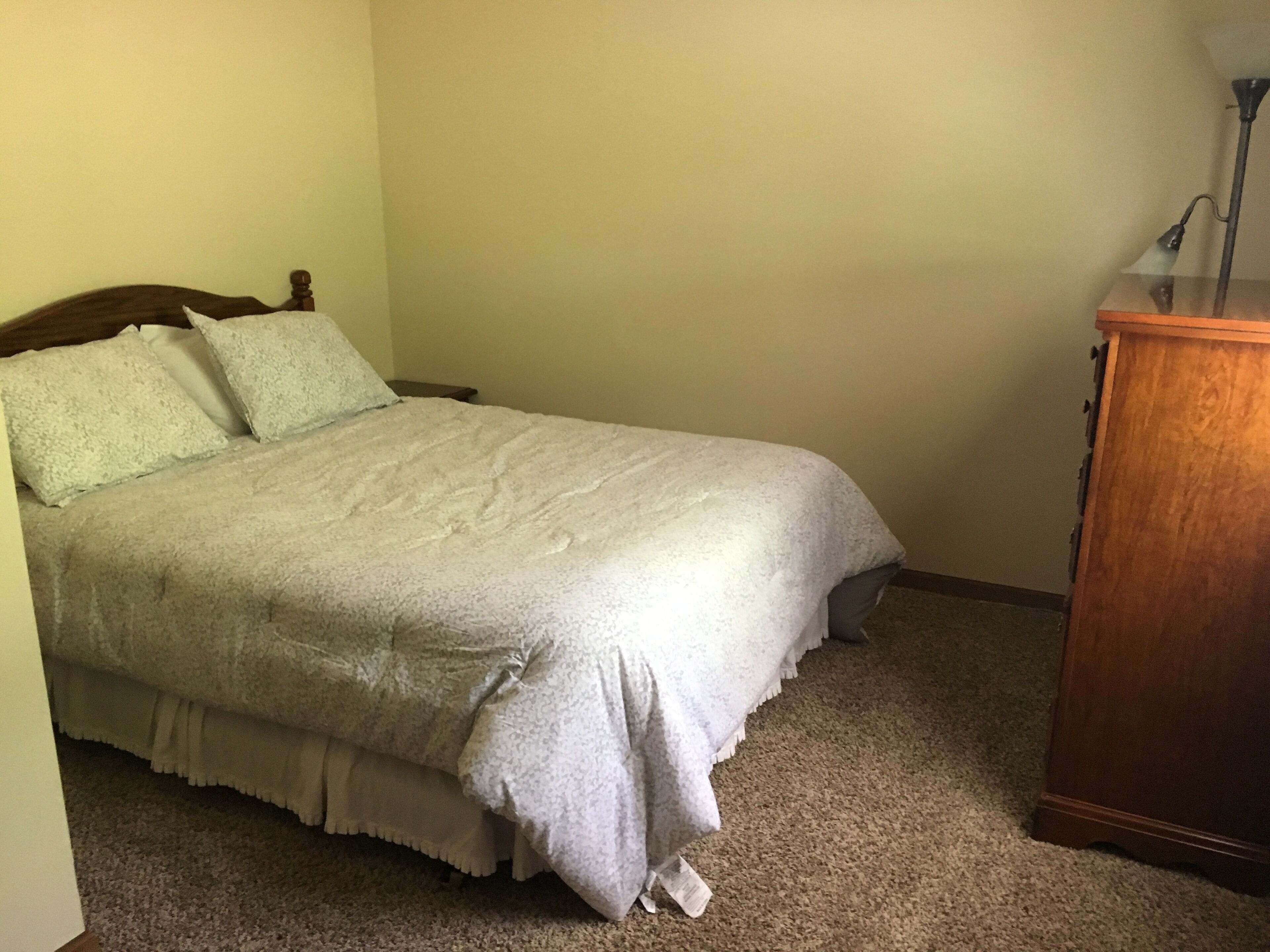 Ein Schlafzimmer mit einem Bett, einem Nachttisch und einer Holzkommode.