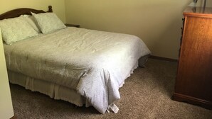 Un dormitorio con una cama, una mesita de noche y un aparador de madera.
