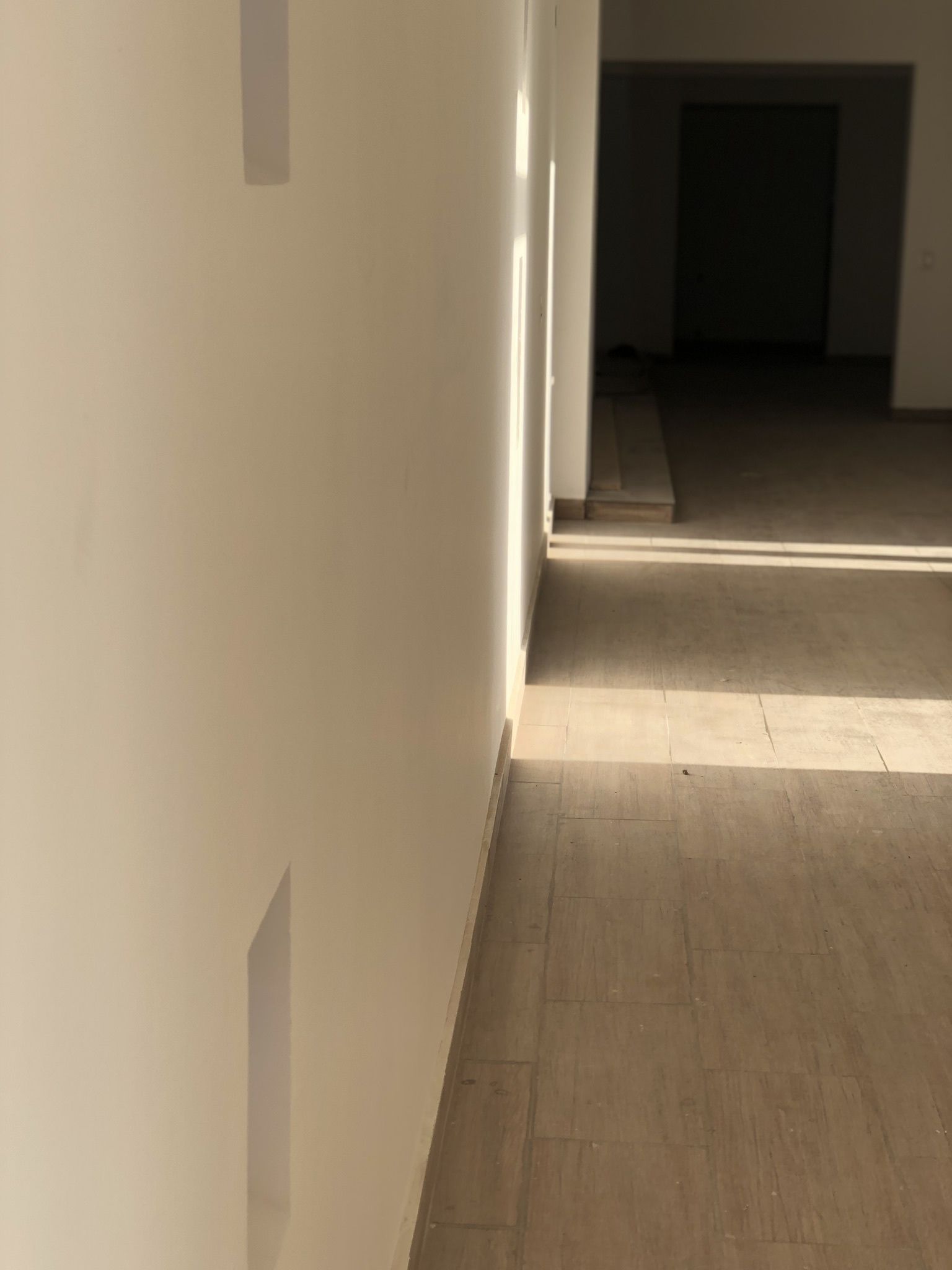 A hallway with a wooden floor and white walls.