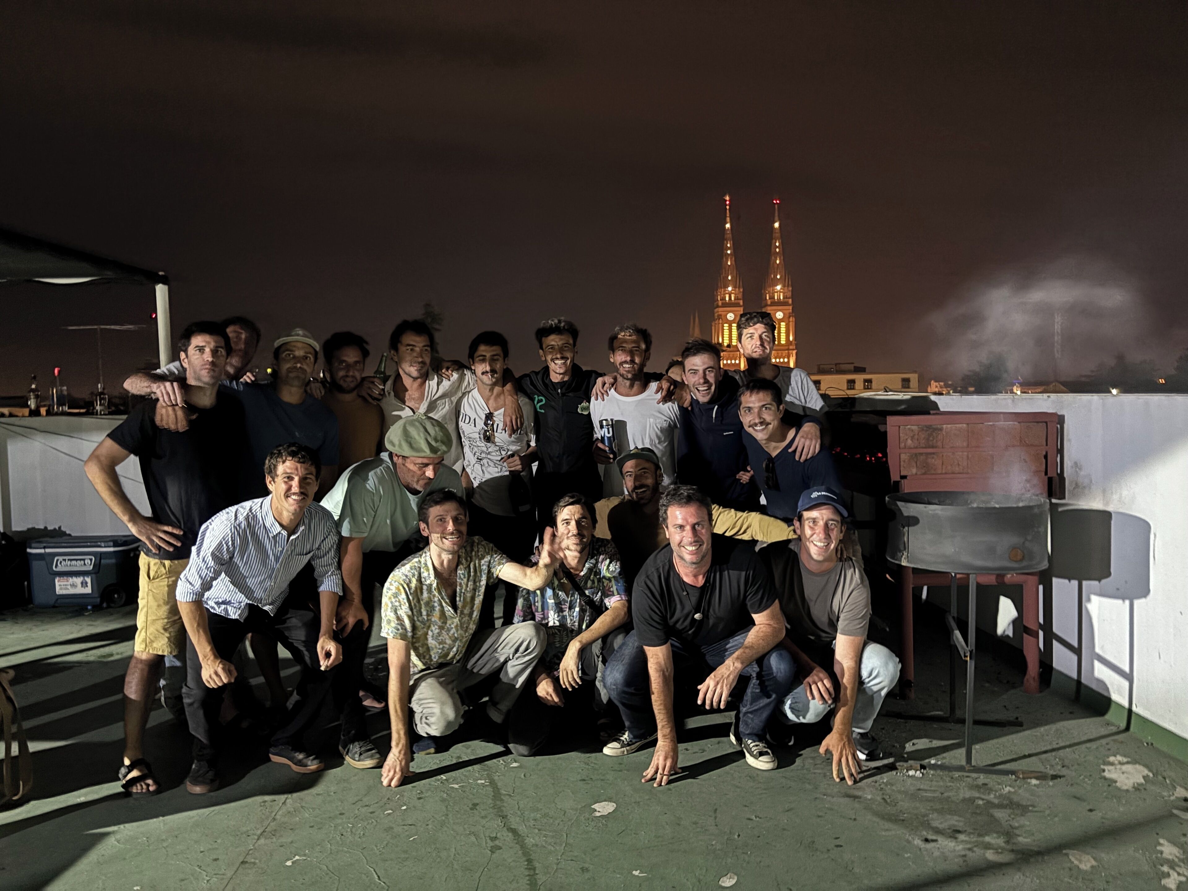 Un grupo de personas en una azotea, con vista a un edificio iluminado al fondo.