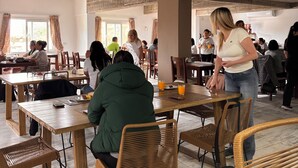 A spacious dining area with wooden tables and chairs, large windows, and a high ceiling with exposed beams. - Lujan Homes Apart Hotel (Luján)