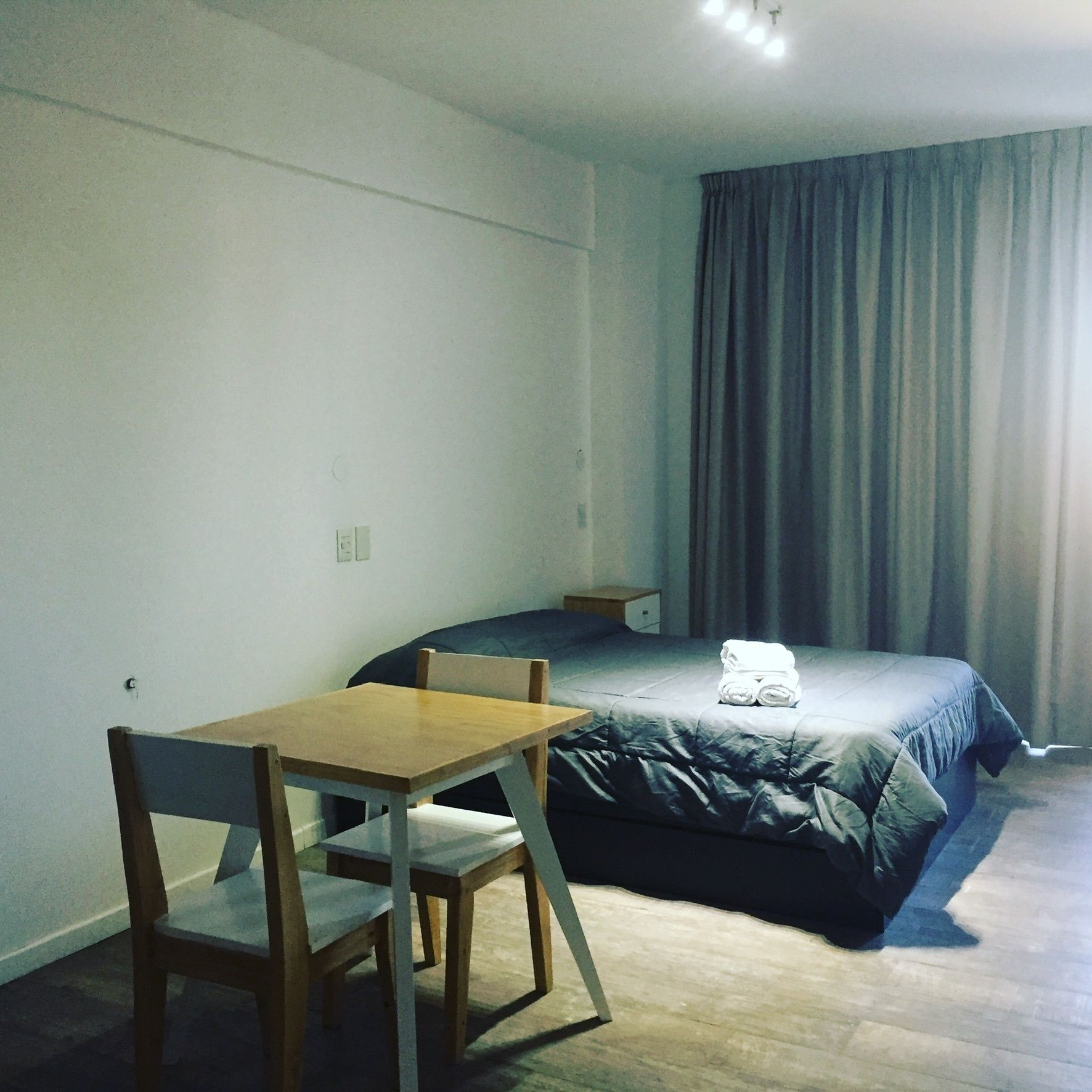 Een kleine, eenvoudige kamer met een bed, een tafel en een stoel.
