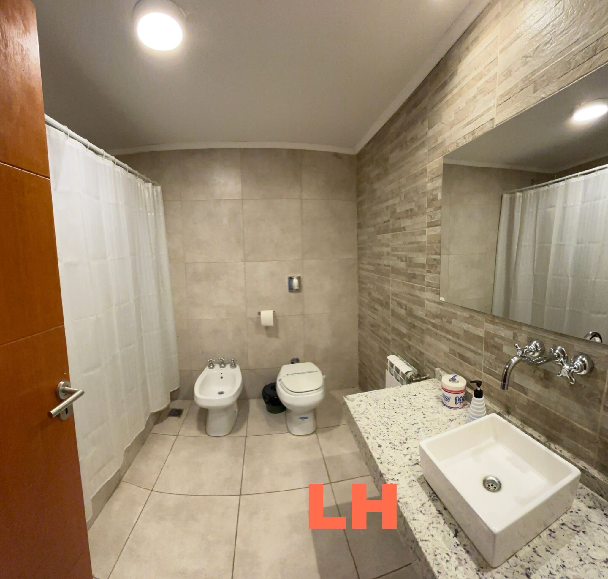 Un baño con dos inodoros, un bidé, un lavabo y un espejo.