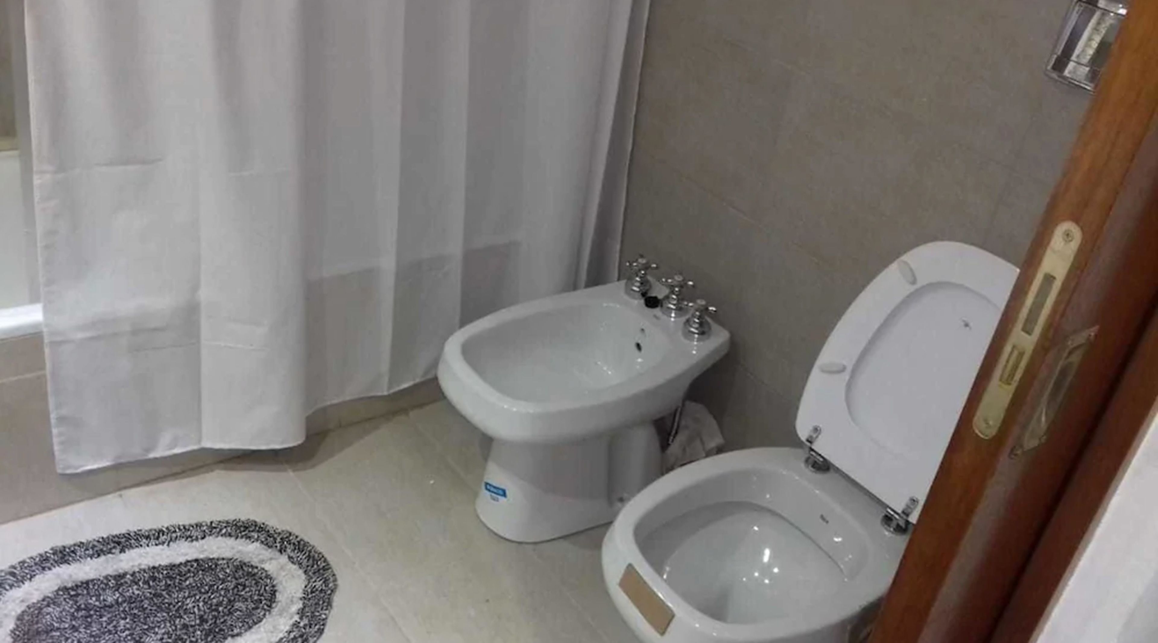A bathroom with a bidet, toilet, and a shower curtain.