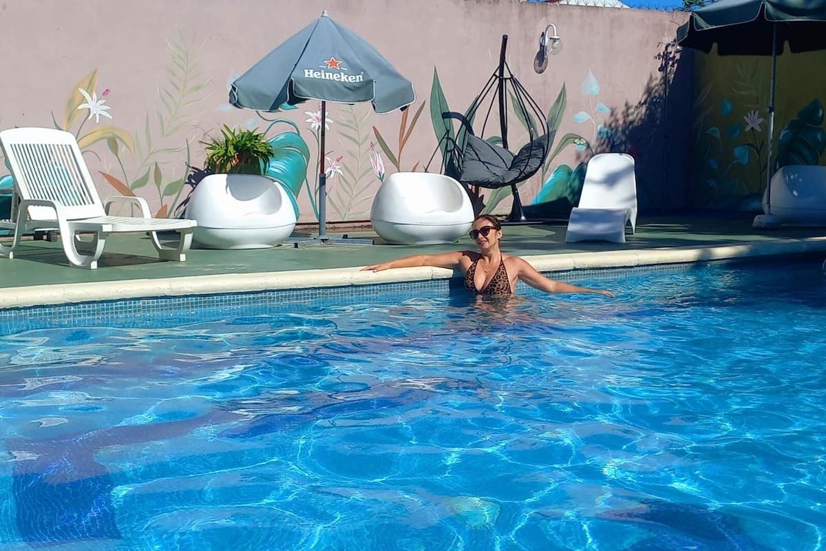 Une piscine avec des chaises longues et un parasol à l’effigie de la marque Heineken.