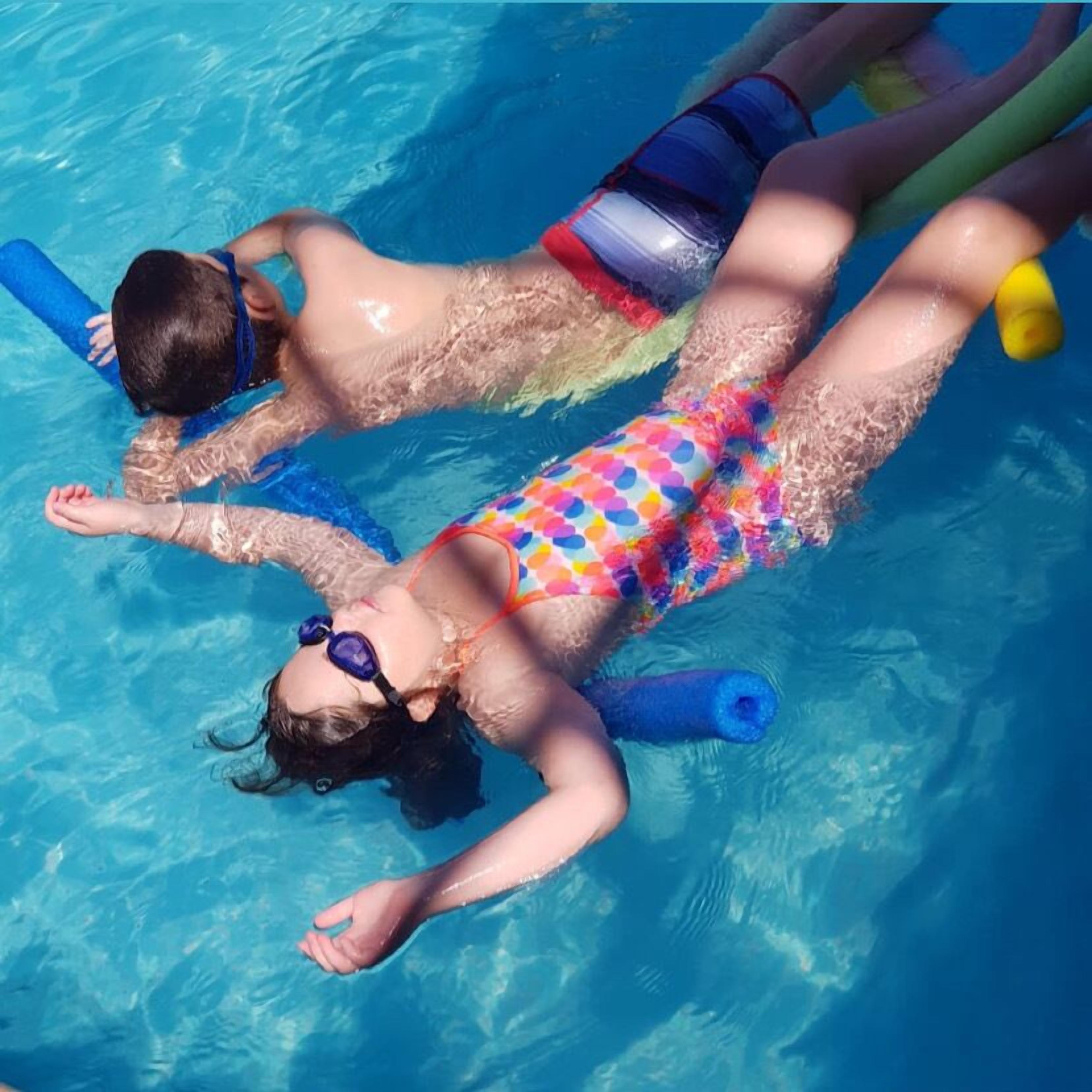 Dos personas flotando en una piscina con flotadores.