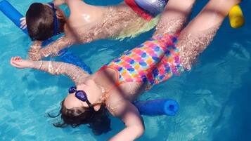 Dos personas flotando en una piscina con flotadores.