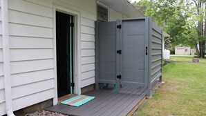 A house with a gray exterior, a wooden deck, and a door leading to a covered porch. - Perfect Maine Getaway – Walk to Downtown, Cozy for All - Flexible Cancellation. (Kennebunk)