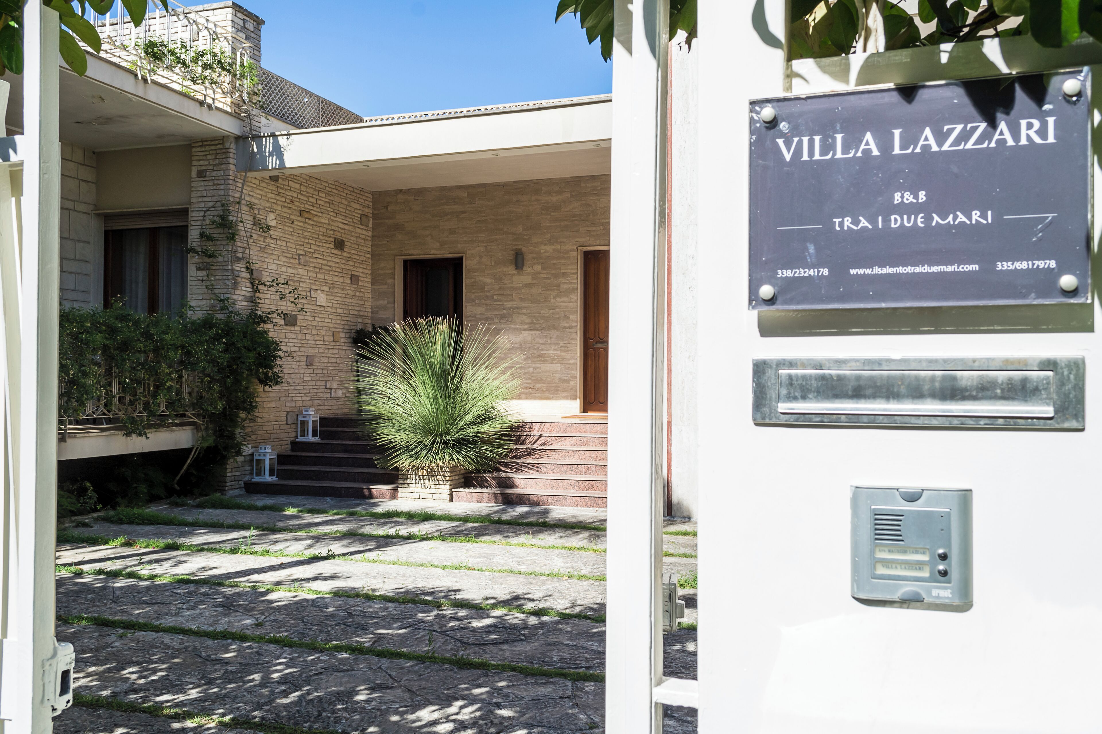 A villa named "Villa Lazzari" with a signboard, a brick exterior, and a small garden area with steps leading to the entrance.