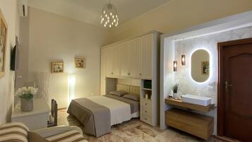 Quarto com cama, mesa de cabeceira, abajur e espelho com iluminação embutida.