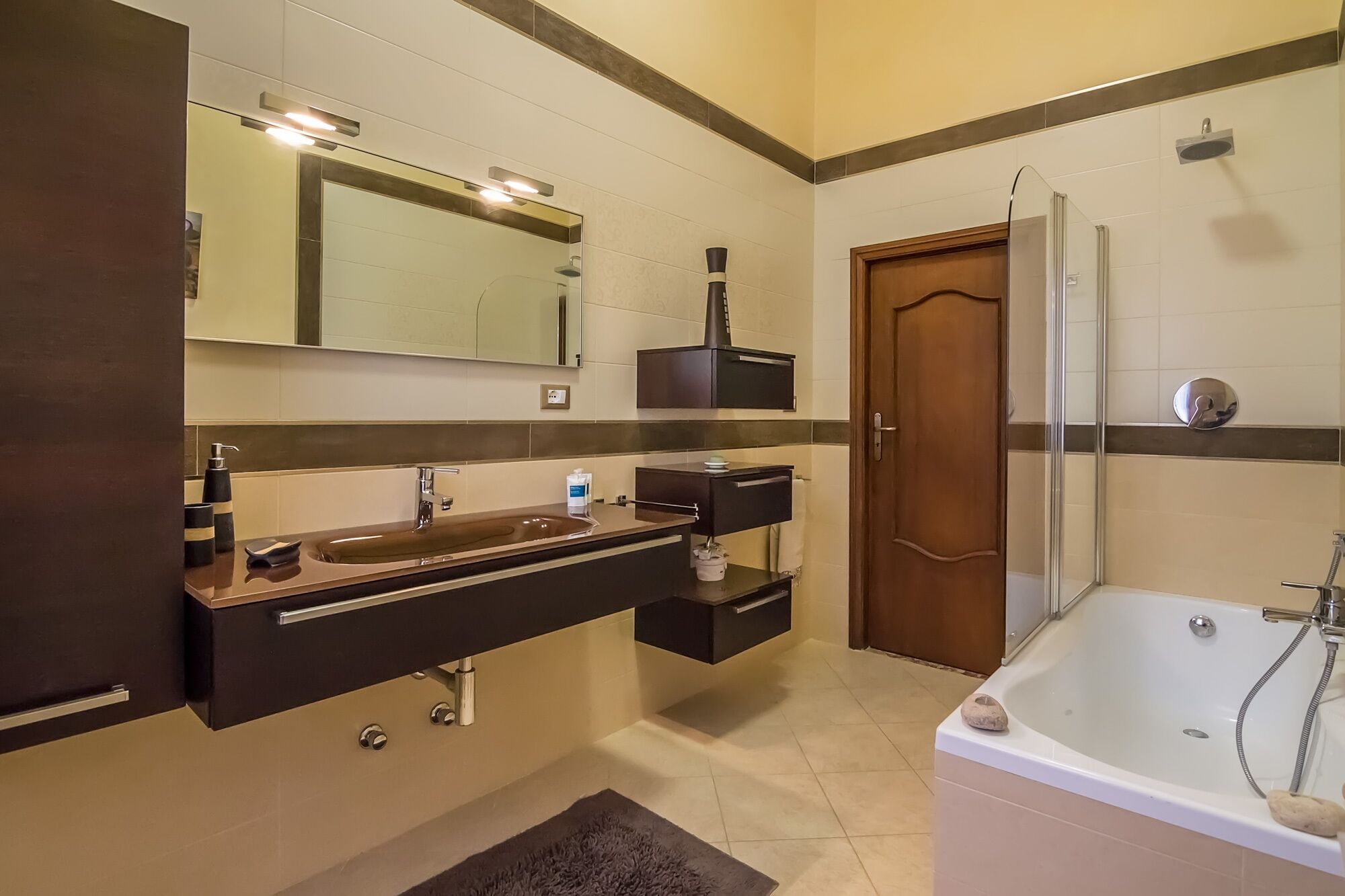 A modern bathroom with a large sink, mirror, and bathtub.