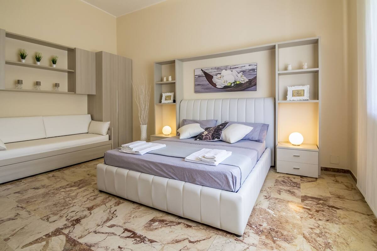 Une chambre moderne avec un grand lit, un canapé et des étagères intégrées.