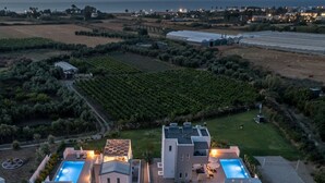 Uma villa moderna com duas piscinas, rodeada por jardins bem cuidados e vinhedos.