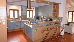 A modern kitchen with granite countertops, stainless steel appliances, and a central island with bar stools. - Spacious villa in beautiful surroundings (São Teotónio)