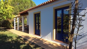 A building with a tiled roof, white walls, and blue doors. There are columns and a covered patio area. - Spacious villa in beautiful surroundings (São Teotónio)