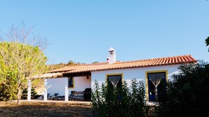 A white building with a red-tiled roof, a bell tower, and a covered patio with chairs. - Spacious villa in beautiful surroundings (São Teotónio)