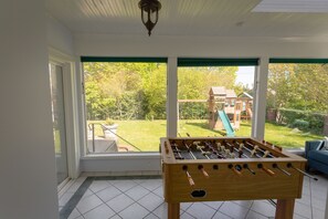 Enjoy a view of the backyard from this room, featuring a foosball table and a large window.