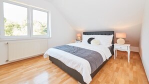 Un dormitorio con cama, dos mesitas de noche, una ventana y un radiador.