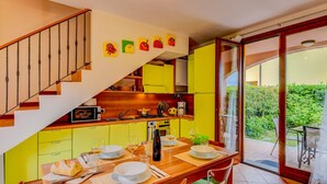 Eine moderne Küche mit gelben Schränken, einer Holztreppe und einem Essbereich mit Tisch für vier Personen.