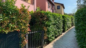 Ein Weg, der von ordentlich geschnittenen Hecken und einem Gebäude mit Balkon gesäumt wird.