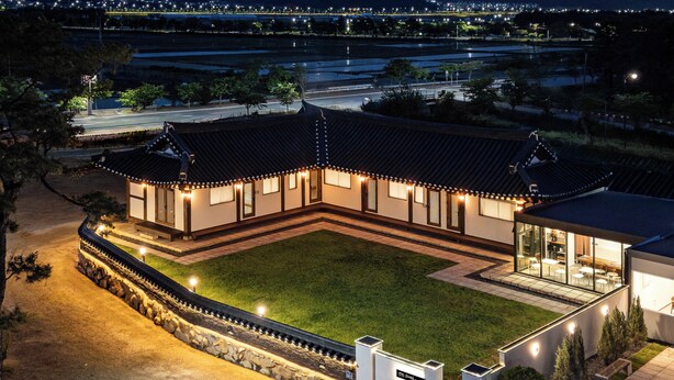 A traditional building with a courtyard, surrounded by a stone wall, and a modern extension with glass windows. - Hwarangroo (Gyeongju)