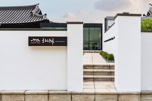 A modern building with a traditional Korean roof, a sign reading 'hanok stay,' and a staircase leading to the entrance. - Hwarangroo (Gyeongju)