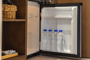 Un refrigerador con dispensador de agua y cuatro botellas.