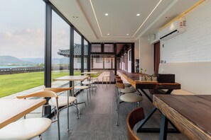 A modern dining area with tables and chairs, large windows, and a view of the outdoors. - Hwarangroo (Gyeongju)