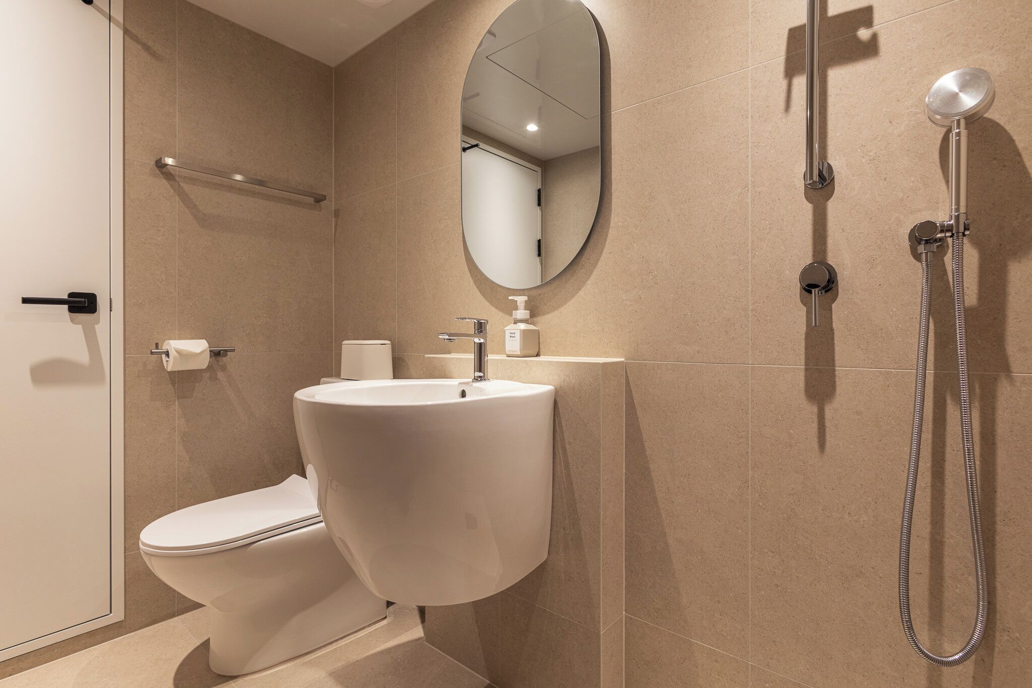 A modern bathroom with a toilet, sink, mirror, and shower.