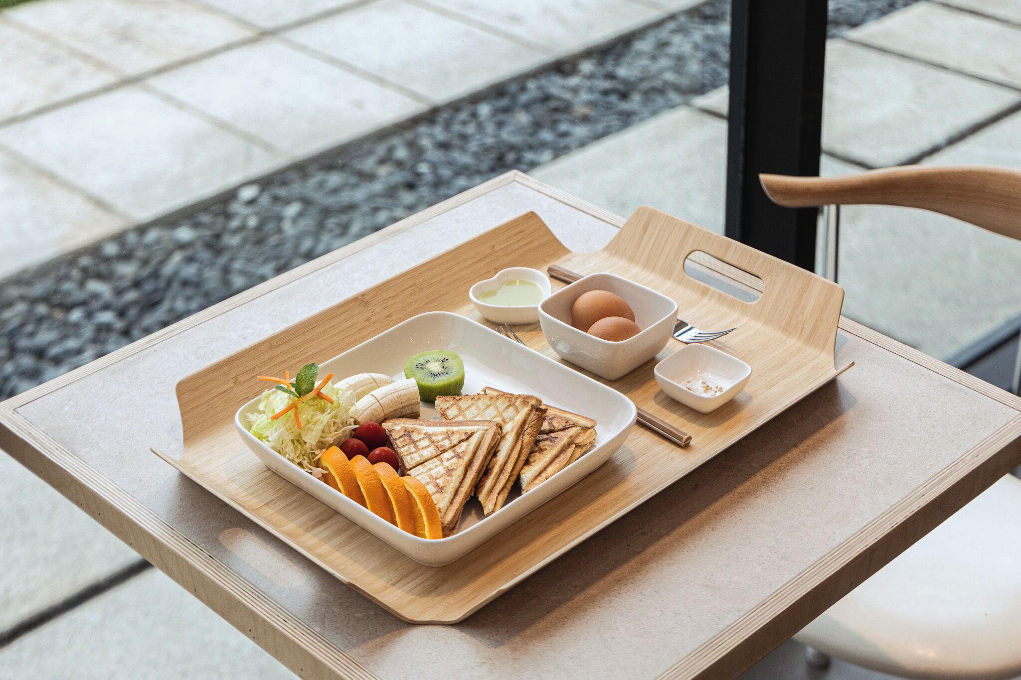 A tray with sandwiches, fruits, and condiments on a table.