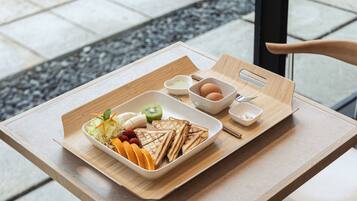 A tray with sandwiches, fruits, and condiments on a table.