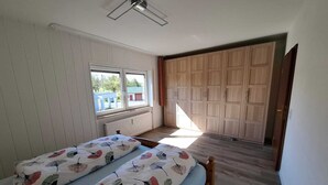 Un dormitorio con dos camas, una ventana, un radiador y un armario.