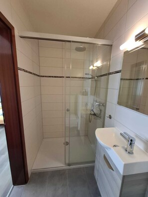 Een bad/douchecombinatie, een haardroger, handdoeken, zeep