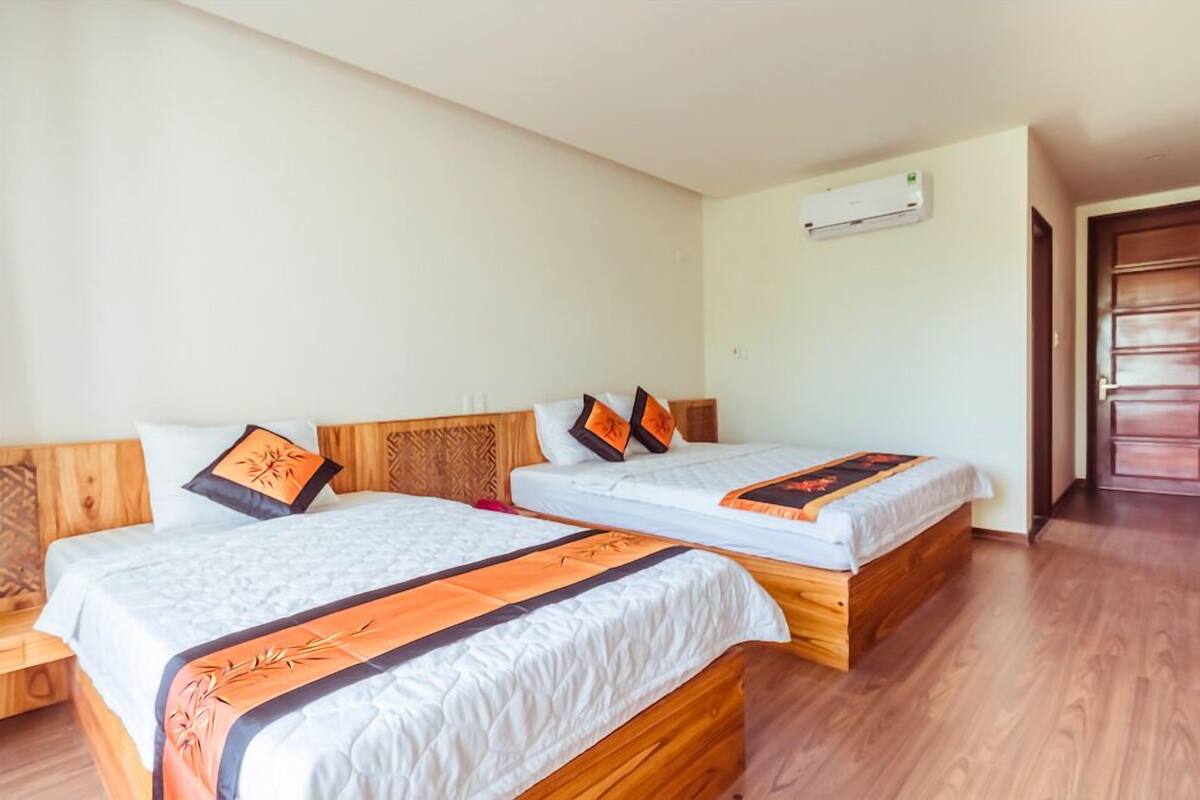 A hotel room with two wooden beds, white bedding, and a wooden headboard.