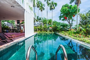 A swimming pool with a clear blue water, surrounded by lush greenery and palm trees. - Opal Boutique Villa (Da Nang)