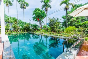A swimming pool with a metal handrail, surrounded by lush greenery and palm trees. - Opal Boutique Villa (Da Nang)