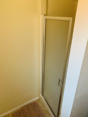 A corner of a room with a glass door, beige walls, and a brown rug. - The Gathering Place 3BR + Game Room (Keizer)
