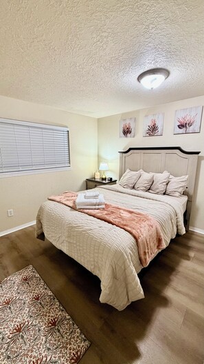 Un dormitorio con cama, mesita de noche, lámpara y decoración en la pared.