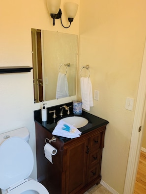A bathroom with a toilet, sink, and vanity. - The Gathering Place 3BR + Game Room (Keizer)