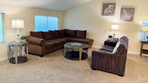 A living room with a sectional sofa, a round coffee table, and two side tables with lamps.