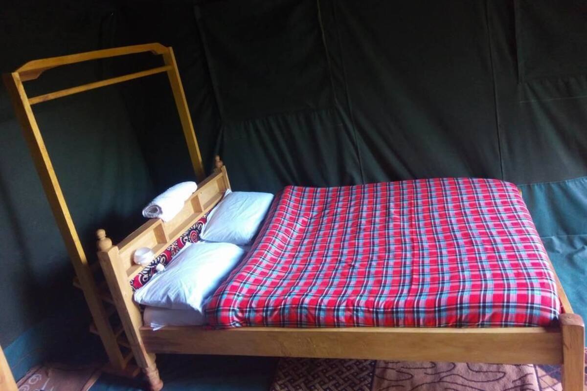 A single bed with a wooden frame and a red plaid bedspread.