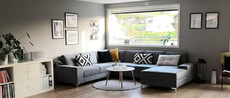A modern living room with a grey sofa set, a coffee table, and a dining area with a white table and chairs.